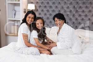 Portrait of multi-generation family sitting on bed