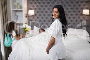 Smiling nurse standing by patient on bed at home