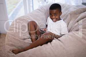 Portrait of smiling boy using mobile phone while sitting on couch at home