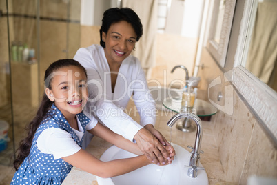 Portrait of grandmother and granddaughter washing hands