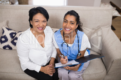 Portrait of smiling patient sitting with doctor checking medical report