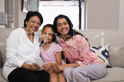 Portrait of smiling multi-generation family sitting together on sofa
