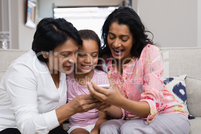Happy multi-generation family using mobile phone while sitting together