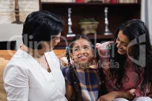 Cute smiling girl with mother and grandmother sitting at home