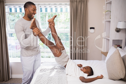 Cheerful father playing with son in bedroom