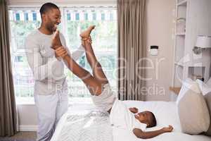 Cheerful father playing with son in bedroom