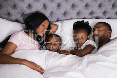 High angle view of family sleeping together on bed