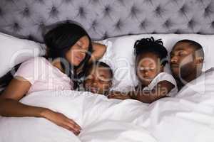High angle view of family sleeping together on bed