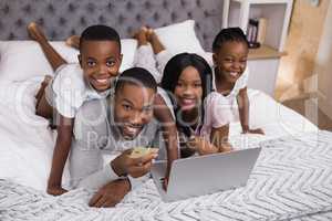 Portrait of happy family shopping online on bed