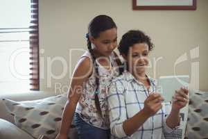 Mother and daughter using digital tablet in living room