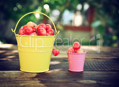 Ripe cherry in an iron bucket on a wooden surface