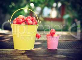 Ripe cherry in an iron bucket on a wooden surface