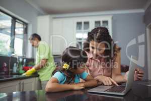 Mother and daughter using laptop in kitchen