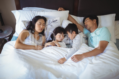Family sleeping on bed in the bed room