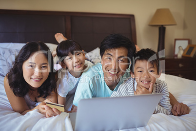 Happy family doing online shopping on laptop in the bed room