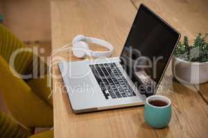 Laptop with headphones and cup on table