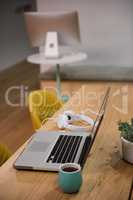 Laptop with headphones and cup on table