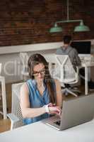 Female executive adjusting smart watch at desk