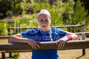 Fit woman leaning on hurdles during obstacle course training in the boot camp