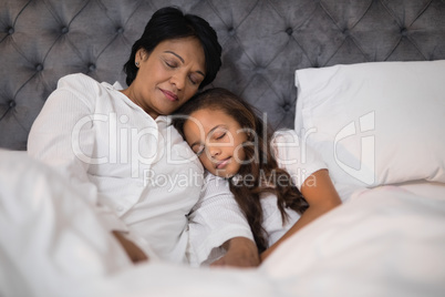 Low angle view of grandmother and granddaughter napping on bed