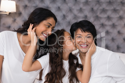 Girl loving mother and grandmother in bedroom