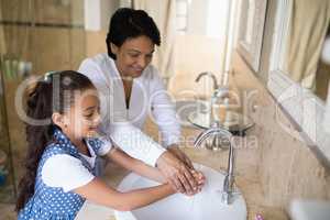 Grandmother and granddaughter washing hands at bathroom sink
