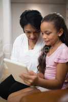 Girl using digital tablet while sitting with grandmother