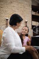 Smiling girl with grandmother holding laptop at home