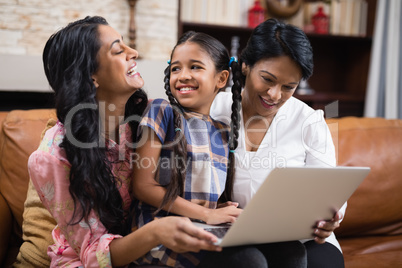 Happy multi-generation family using laptop while sitting together