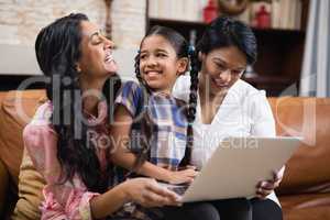 Happy multi-generation family using laptop while sitting together