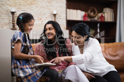 Happy multi-generation family using digital tablet together at home