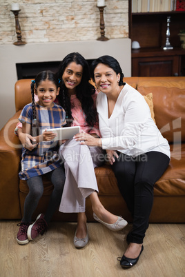 Portrait of smiling multi-generation family using digital tablet at home
