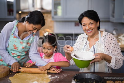 Portrait of woman preparing food with family in kitchen