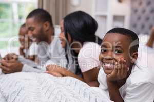 Portrait of smiling boy lying with family on bed