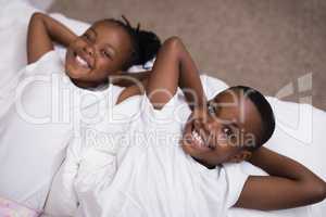 Portrait of smiling siblings lying together on bed