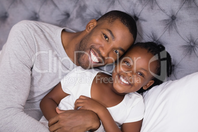 Portrait of man with daughter lying on bed