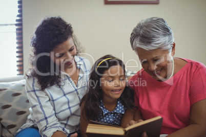 Mother and daughter reading book in living room