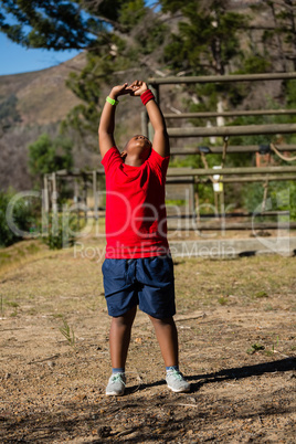 Boy performing stretching exercise during obstacle course training