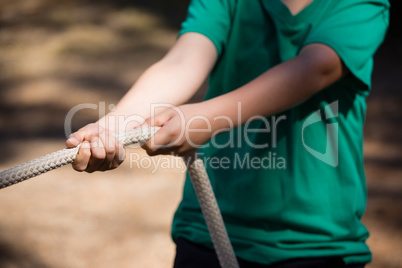 Boy practicing tug of war during obstacle course training in the boot camp