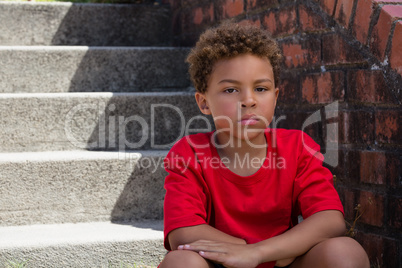 Upset boy sitting on staircase in the boot camp on a sunny day