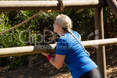 Woman exercising on outdoor equipment during obstacle course training