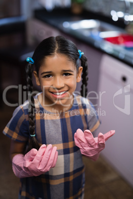 Portrait of smiling girl wearing pink gloves in kitchen