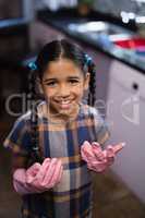 Portrait of smiling girl wearing pink gloves in kitchen