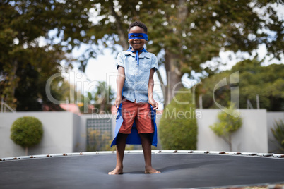 Boy in superhero costume standing on trampoline