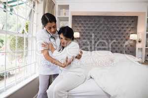 Nurse assisting patient on bed at home