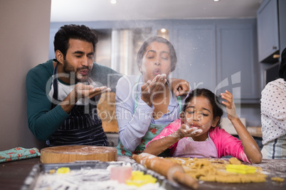 Playful family blowing flour in kitchen