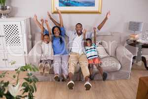 Happy family cheering while sitting on sofa at home
