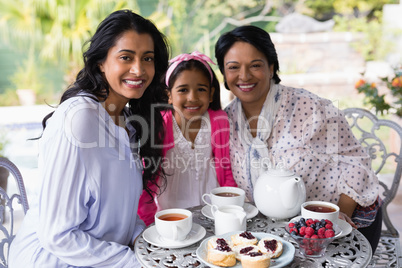Portrait of smiling multi-generation family sitting together by breakfast table