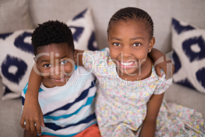 Portrait of smiling siblings sitting on sofa