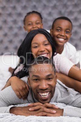 Portrait of smiling man with family lying on bed